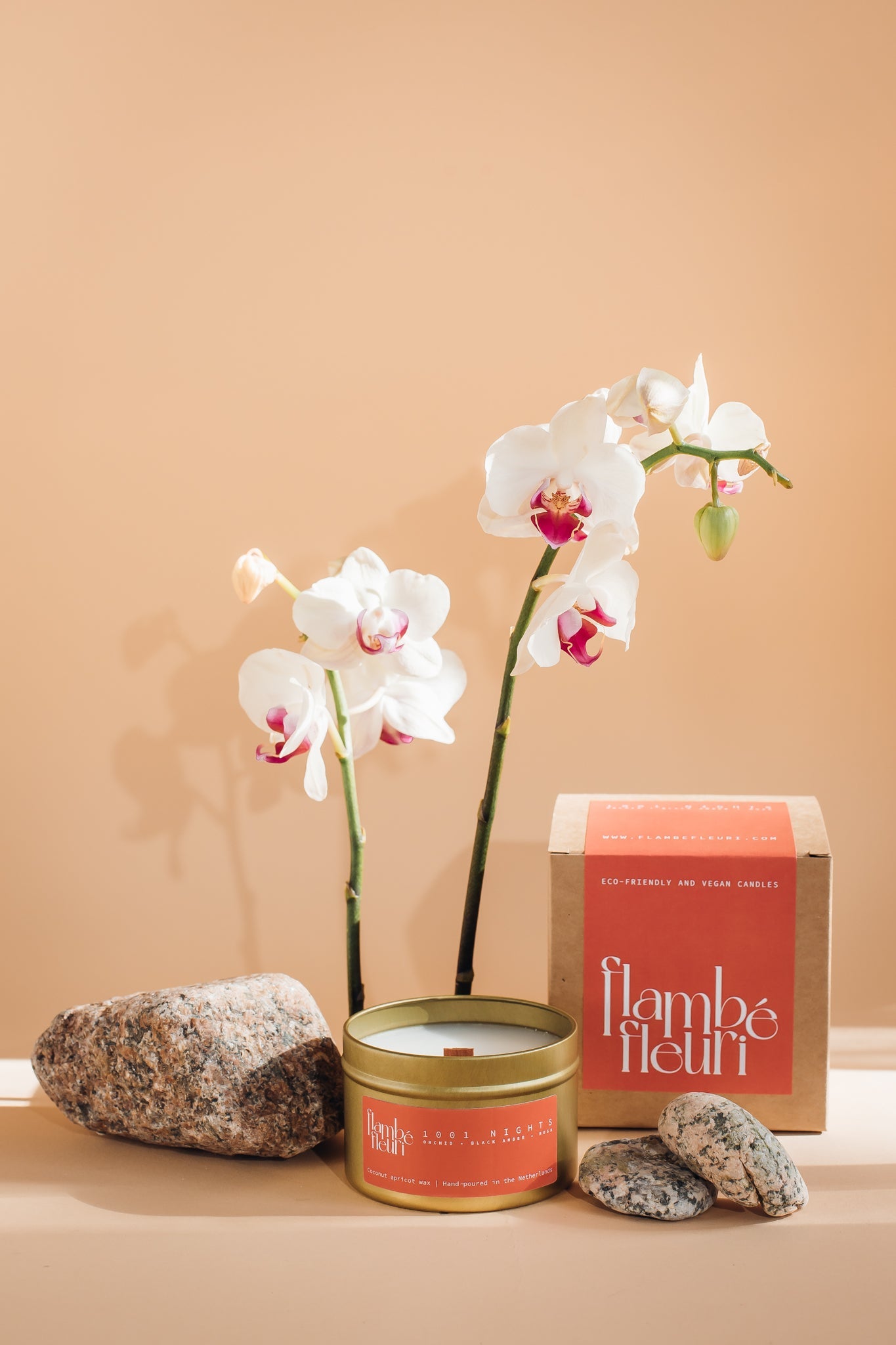 Vegan Scented Candle - Oriental 1001 Nights - Non Toxic. Candle and orchids with 'flambé fleuri' packaging on a beige background