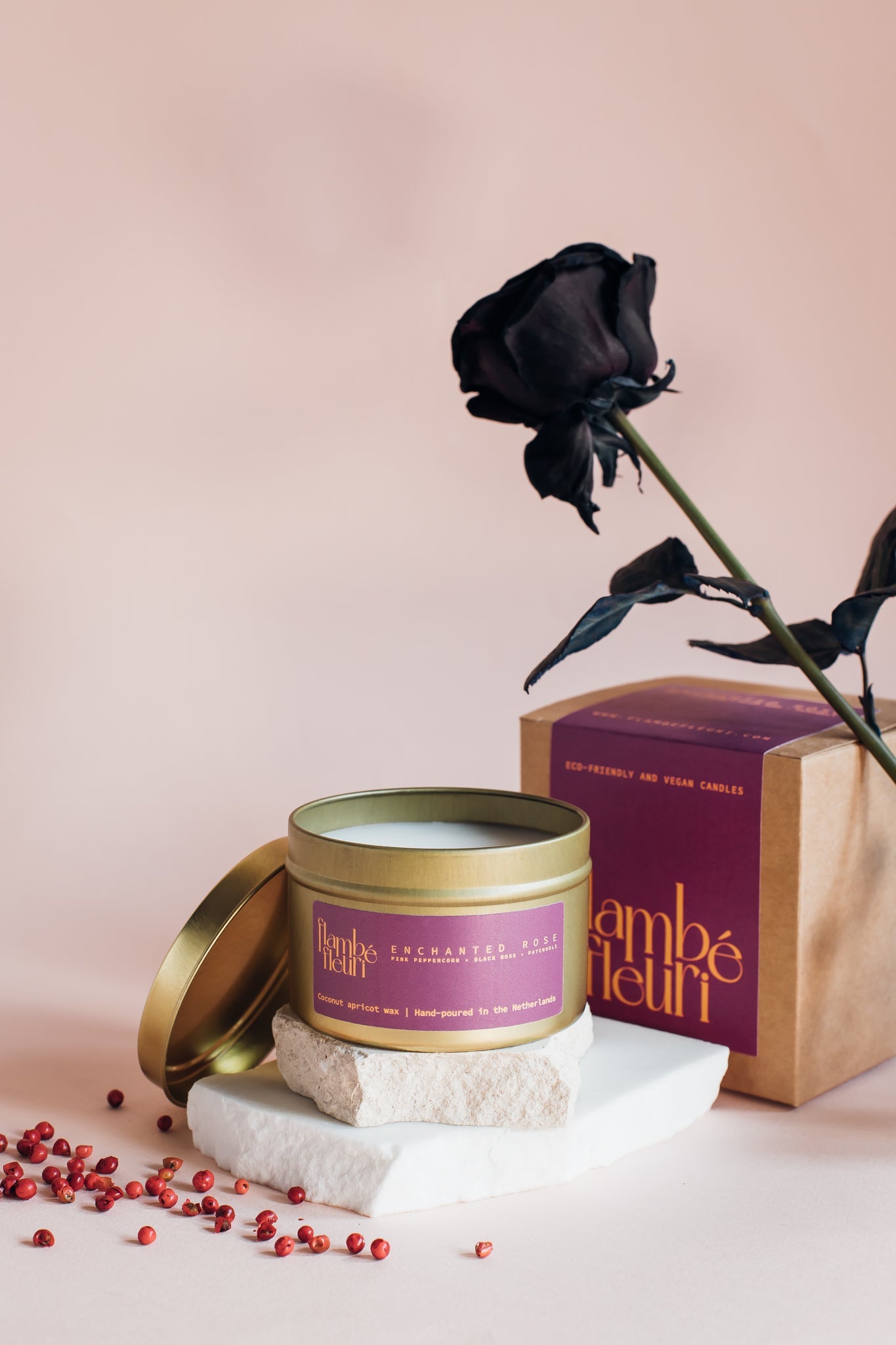 Non toxic Vegan Candle with gold lid, black rose, and decorative stones on a pink background. Wooden wick 